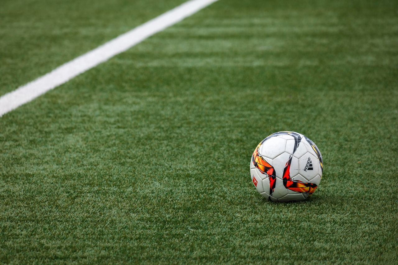 why-choose-us-01 A vibrant soccer ball resting on a pristine grass field beside a white sideline.